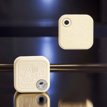 The Curious Mind Rabbit Side-Press Clicker fidget toy in cream, featuring embossed bunny and carrot designs. Metal construction.