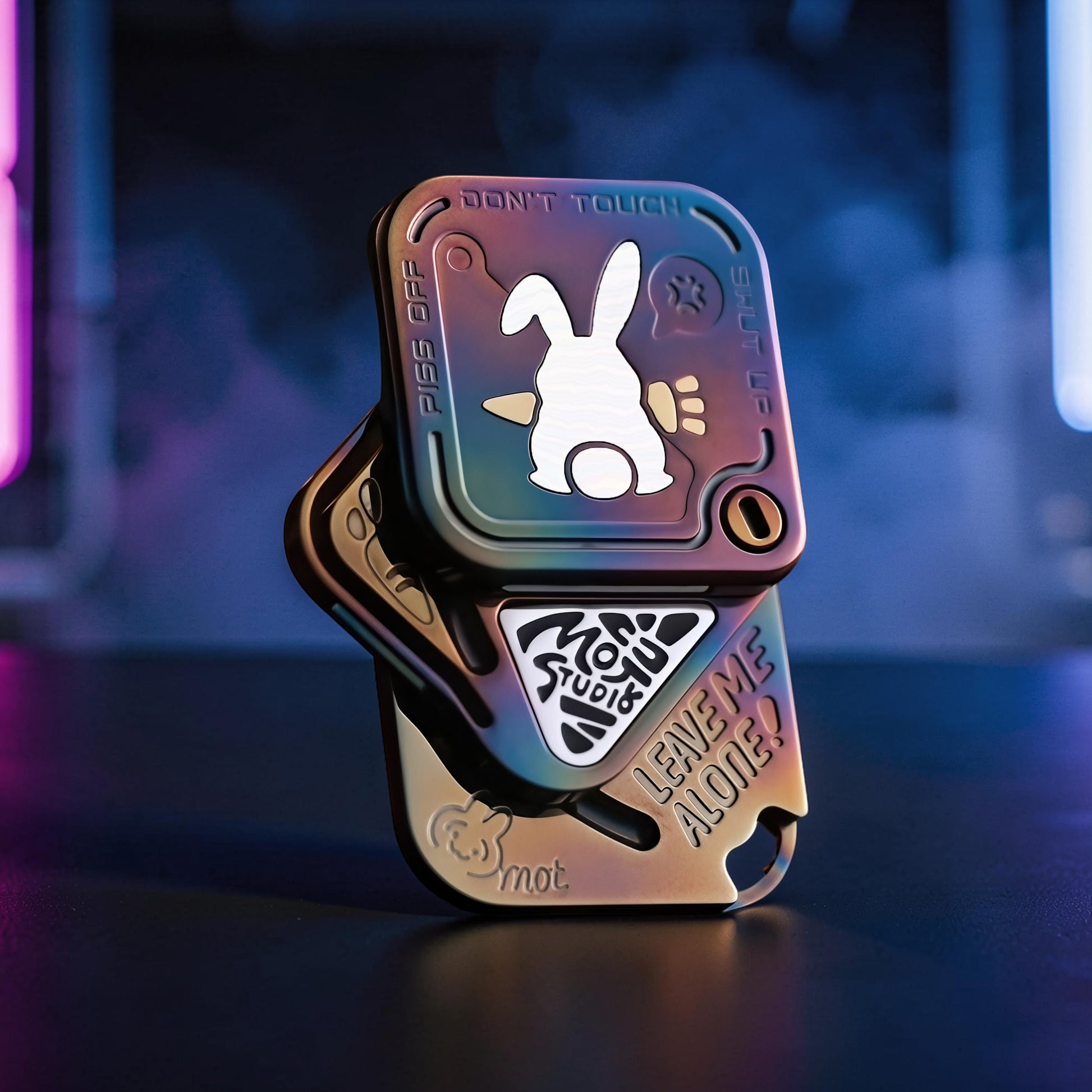 The Curious Mind Rabbit Tuning Fork Clicker fidget toy with a white rabbit graphic and "Don't Touch" text. It has a metallic, iridescent finish and a compact, pocket-friendly design.