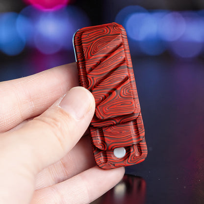 The Curious Mind Three-Layer Push Card Slider fidget toy with red and black wood grain pattern. Compact metal design.