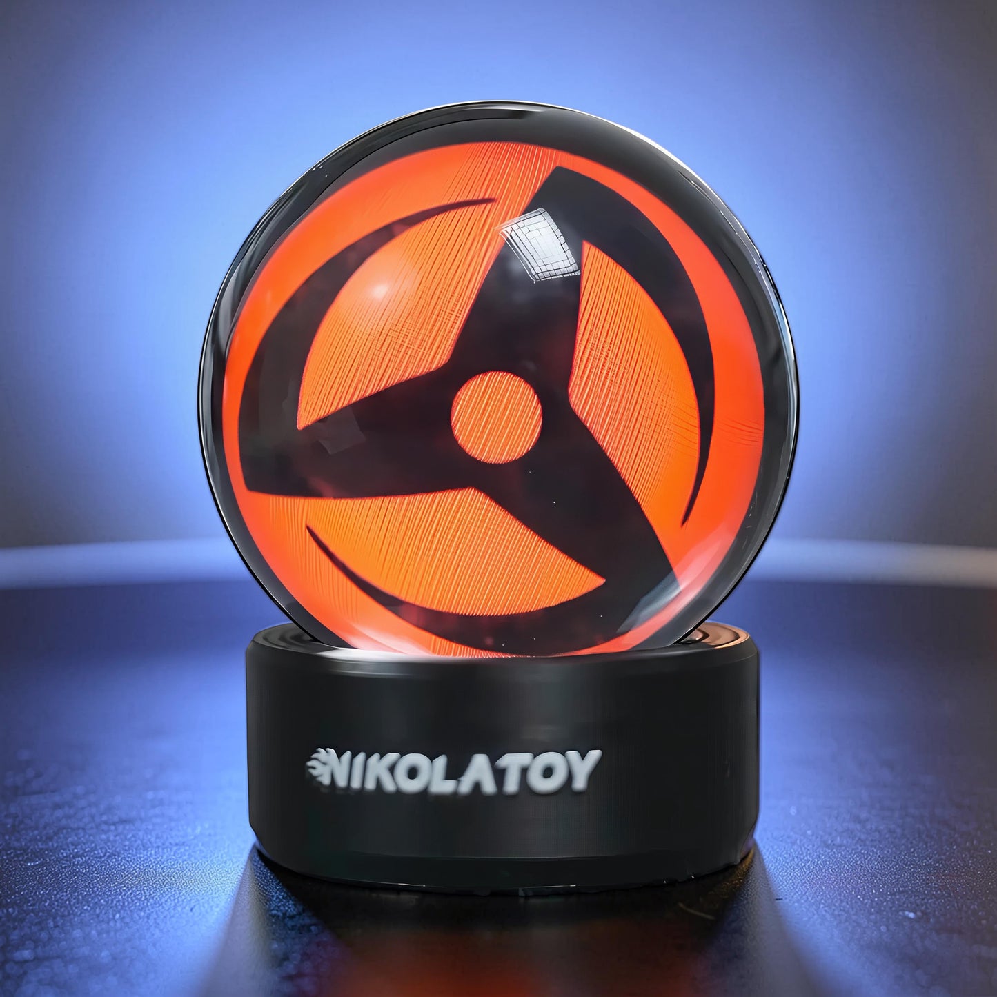 The Curious Mind Sharingan Crystal Ball Decorative Ornament with orange and black design on a black base.