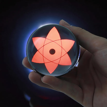 The Curious Mind Sharingan Crystal Ball Decorative Ornament, a red-eyed orb with six petals and a central pupil, held in a hand.