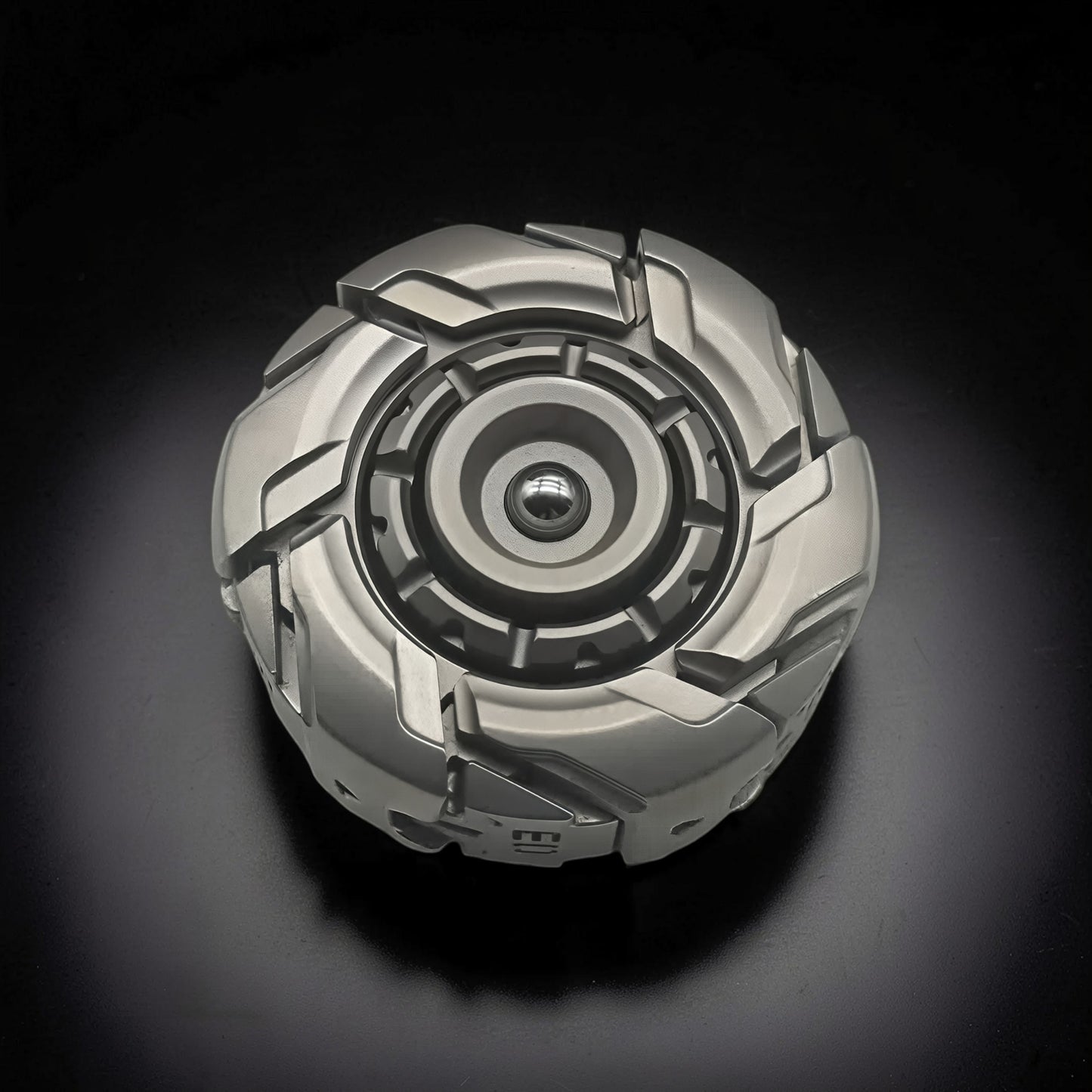 The Curious Mind Open Armour magnetic spinner in silver metal with a complex, segmented design and central bearing.