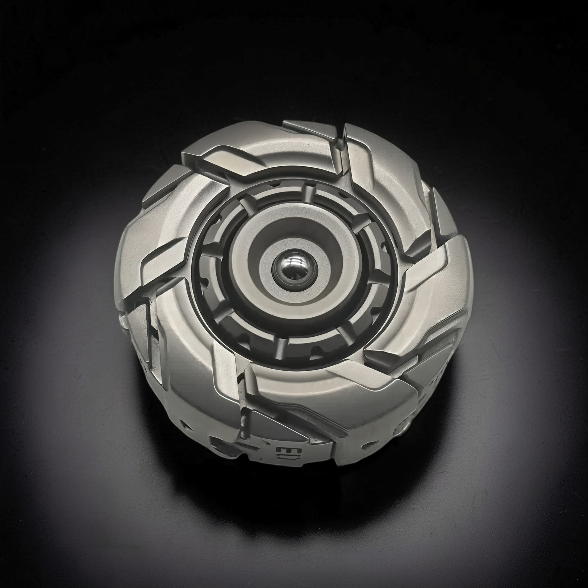 The Curious Mind Open Armour magnetic spinner in silver metal with a complex, segmented design and central bearing.