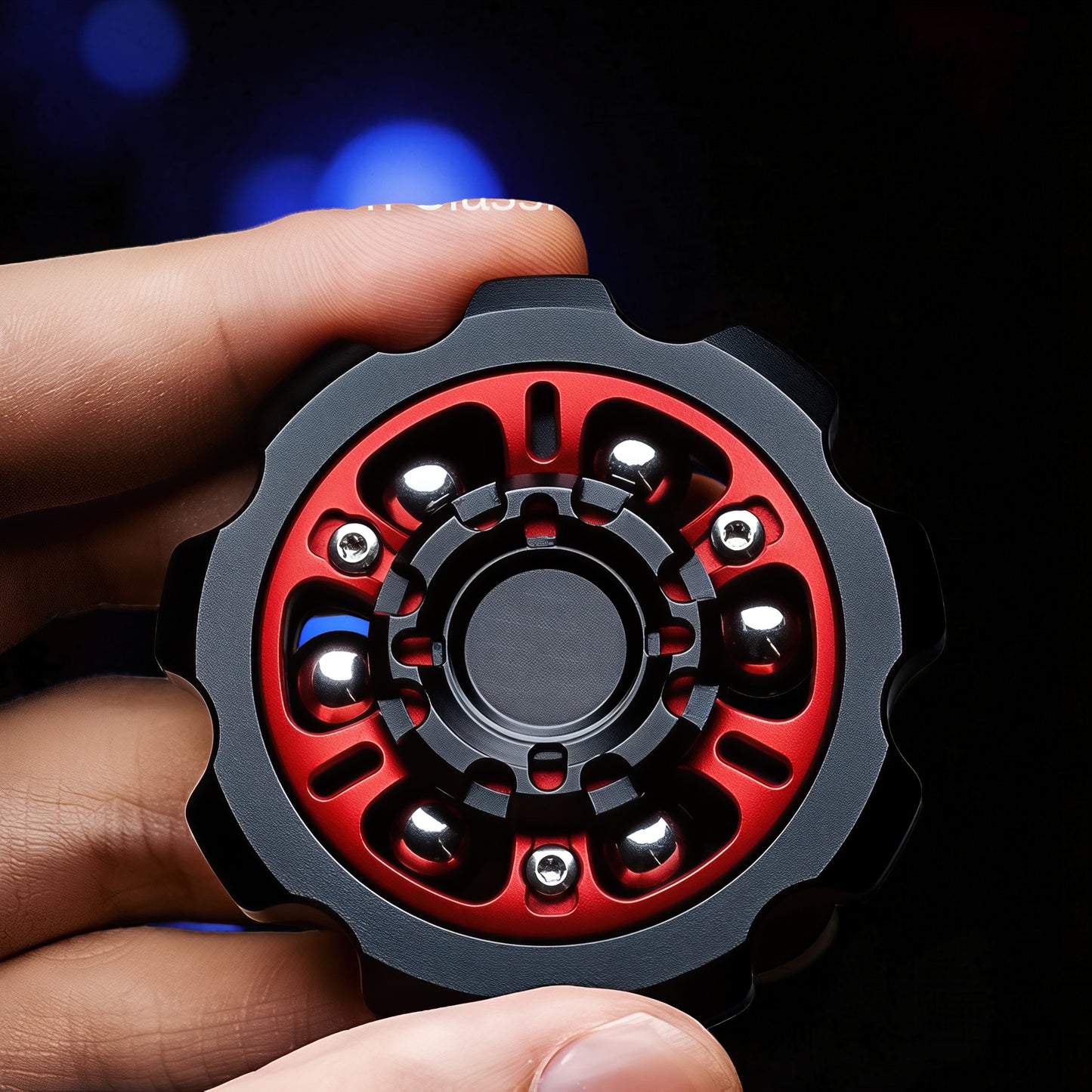 The Curious Mind Six-Bead Gear Spinner, a metal fidget toy with black and red gear-like design and six silver bearings.