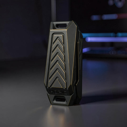 The Curious Mind Stainless Steel Chevron Slider fidget toy with a dark grey and gold chevron design. Compact metal push slider for stress relief.