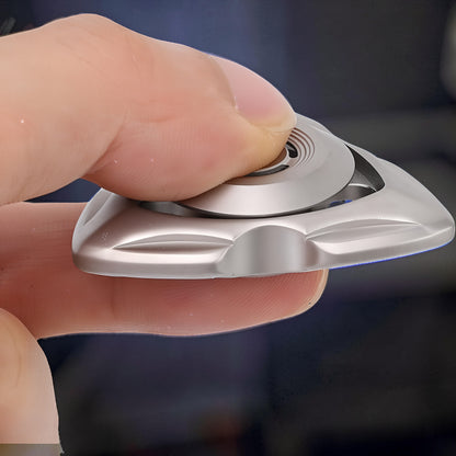 The Curious Mind stainless steel tri-blade spinner with a sleek, metallic finish, held between fingers.