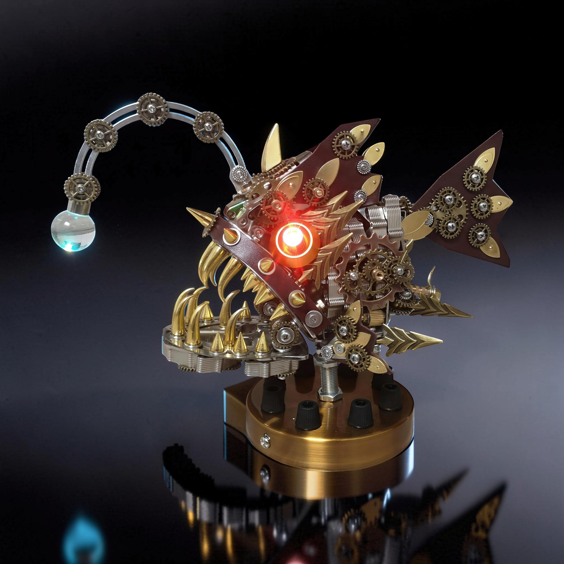 The Curious Mind Steampunk Anglerfish metal model kit with red glowing eye and light-up lure on display base.