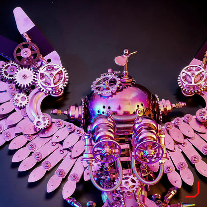 The Curious Mind Steampunk Owl 3D metal model kit with iridescent pink finish, intricate gears, and mechanical wings.