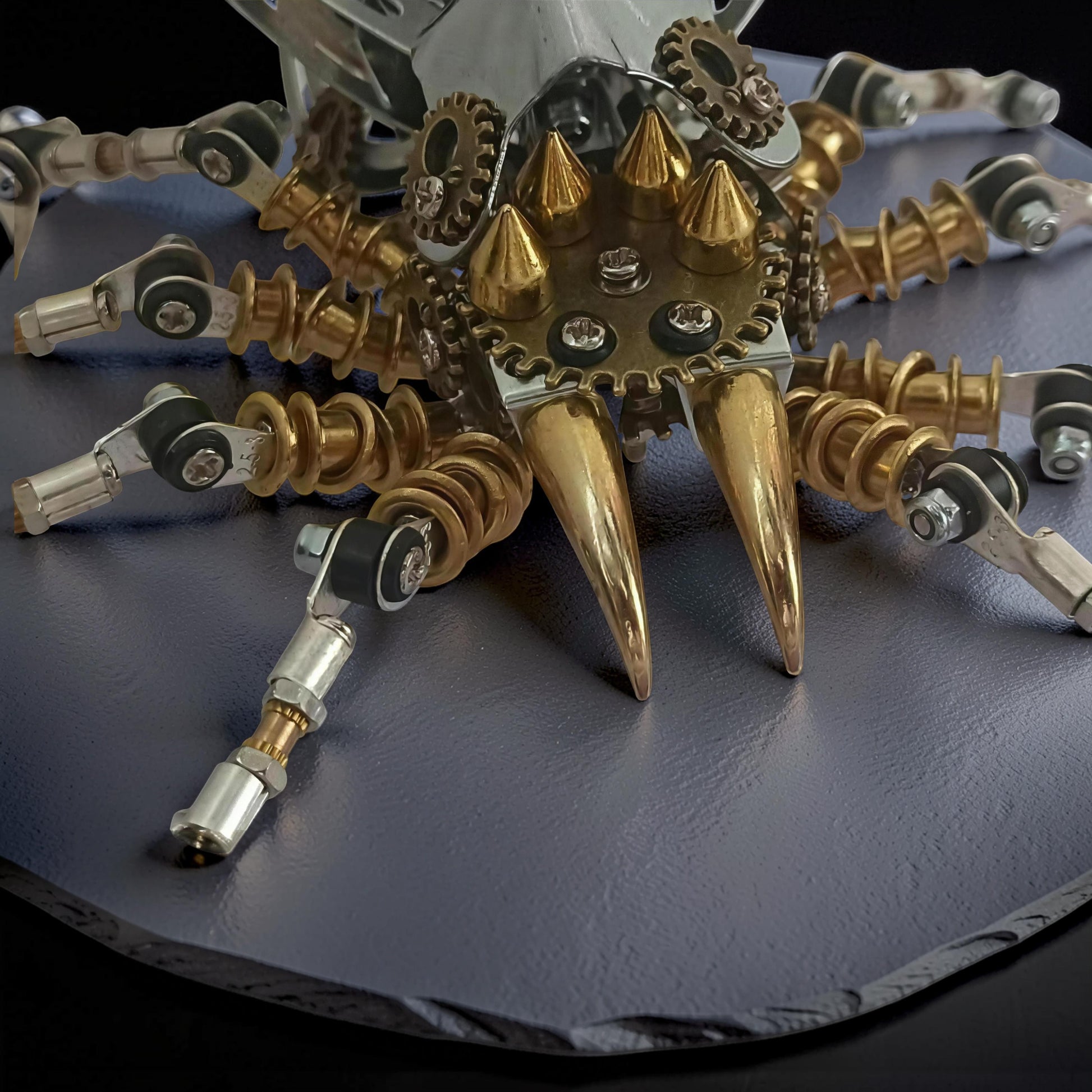 The Curious Mind Steampunk Spider Desk Lamp model kit, featuring metallic gold fangs and gears, with articulated silver and brass legs.