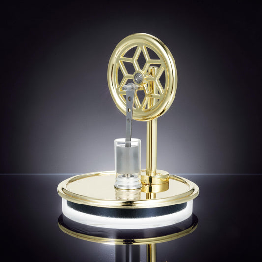 The Curious Mind Temperature Difference Stirling Engine Display Model, a polished gold metal engine with a decorative flywheel and clear cylinder on a reflective base.
