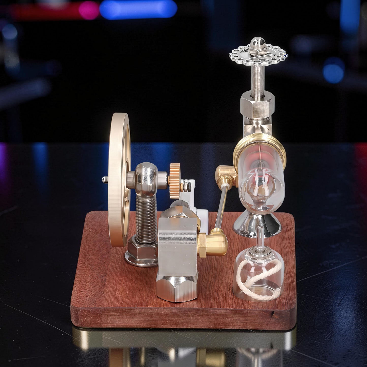 The Curious Mind Stirling Engine with adjustable speed controller, made from metal, wood, and quartz glass, featuring a flywheel and mechanical parts.