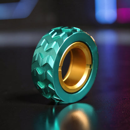 The Curious Mind teal metal tire haptic ratchet ring with gold inner bearing, textured tread for tactile feedback.