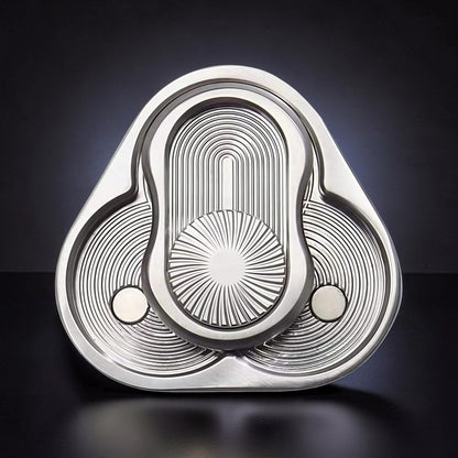 The Curious Mind triangle rotary push card fidget toy, made of silver metal with intricate concentric circle and sunburst patterns.