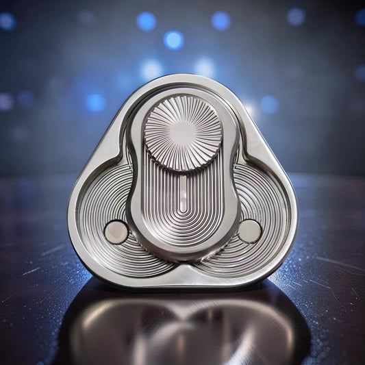 The Curious Mind triangle rotary push card fidget toy, made of silver metal with intricate grooved patterns and a central spinning disc.