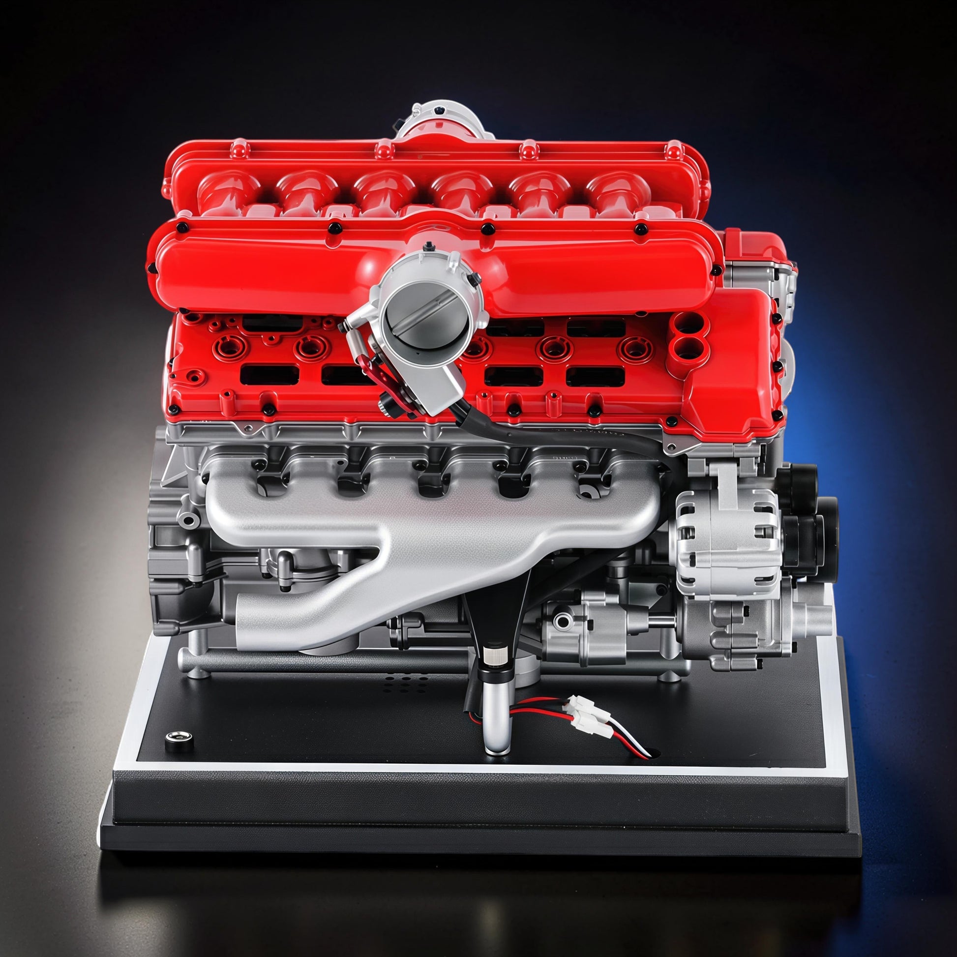 The Curious Mind V12 Car Engine DIY Kit is a detailed metal model with red engine covers and silver components, mounted on a black display base.