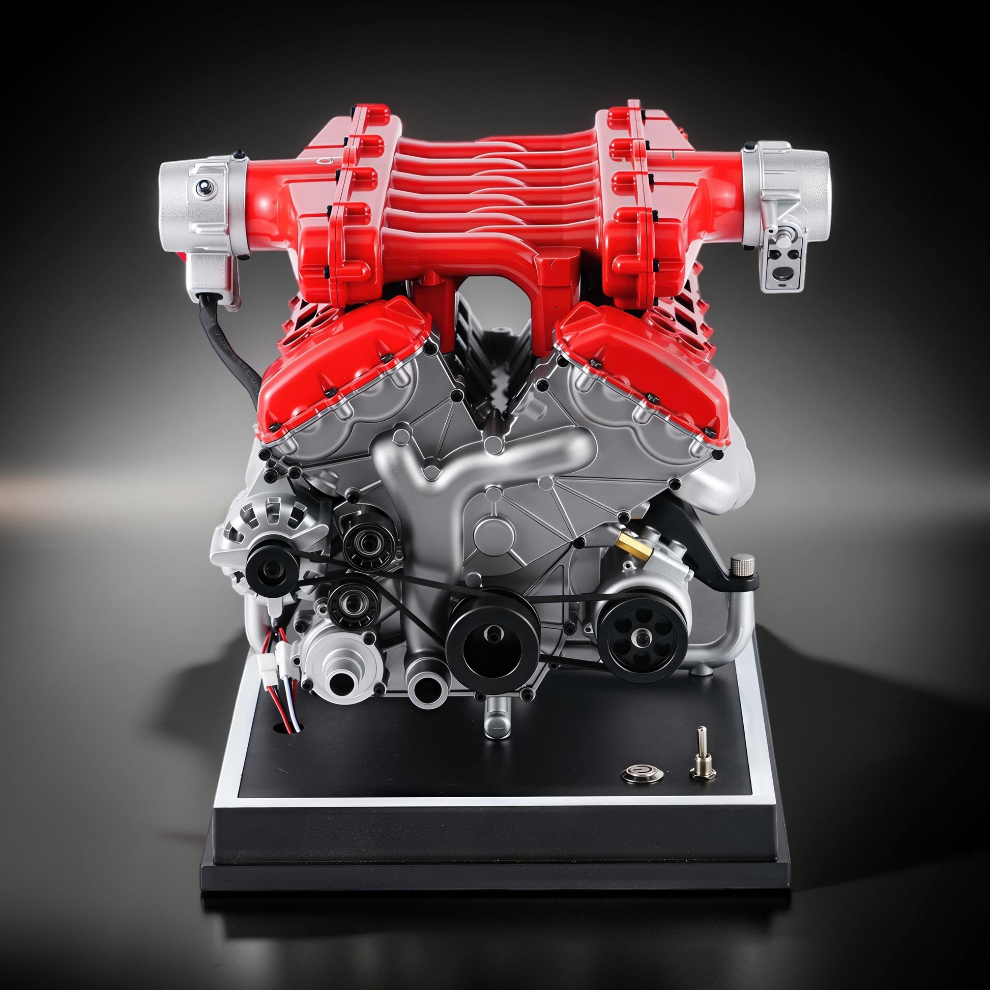 The Curious Mind V12 Car Engine DIY Kit, a detailed metal model with red and silver components, mounted on a black display base.