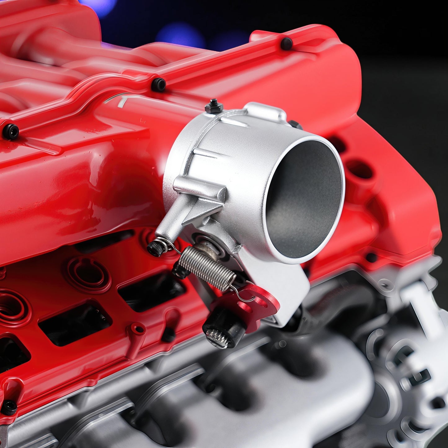 The Curious Mind V12 car engine DIY kit, a detailed metal model with red and silver components, featuring a throttle body and spring mechanism.