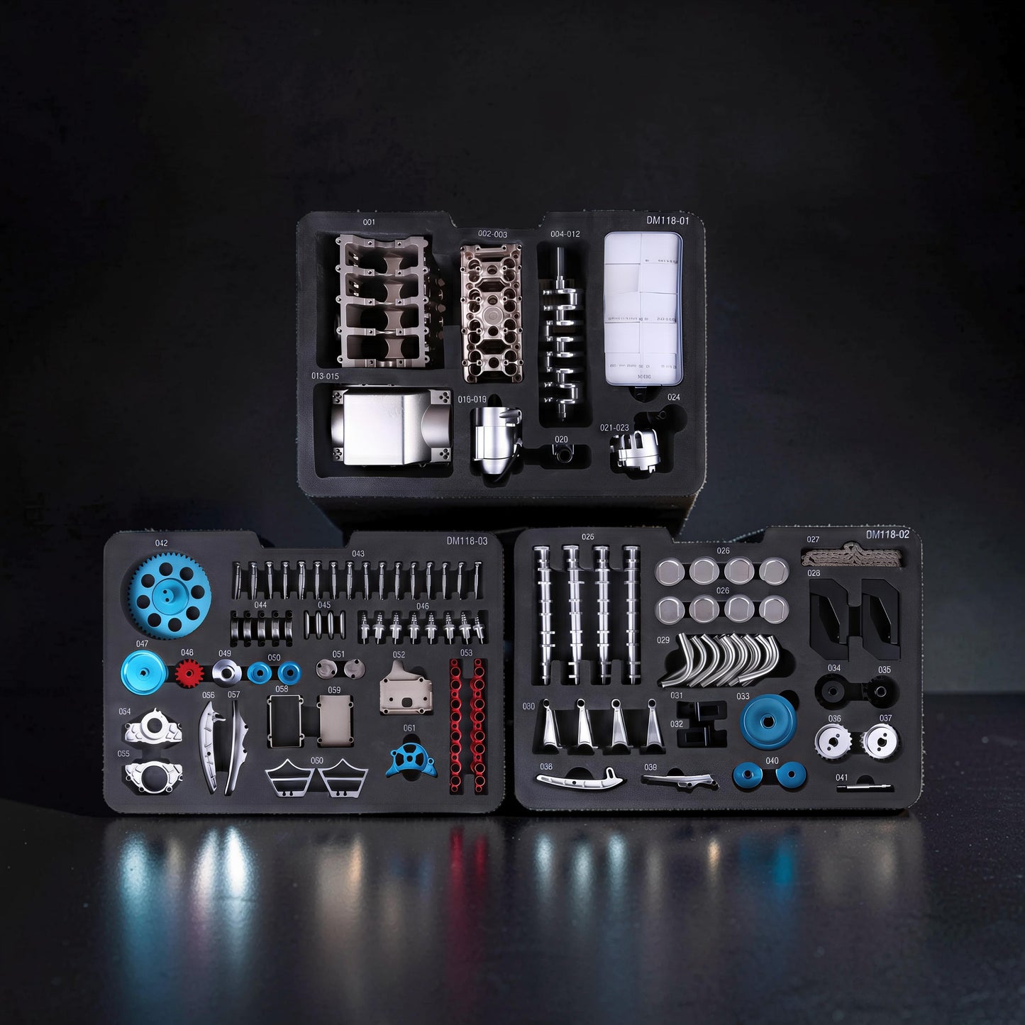 The Curious Mind V8 Car Engine DIY Kit metal mechanical model parts organised in foam trays. Includes engine block, crankshaft, pistons, gears, and screws.