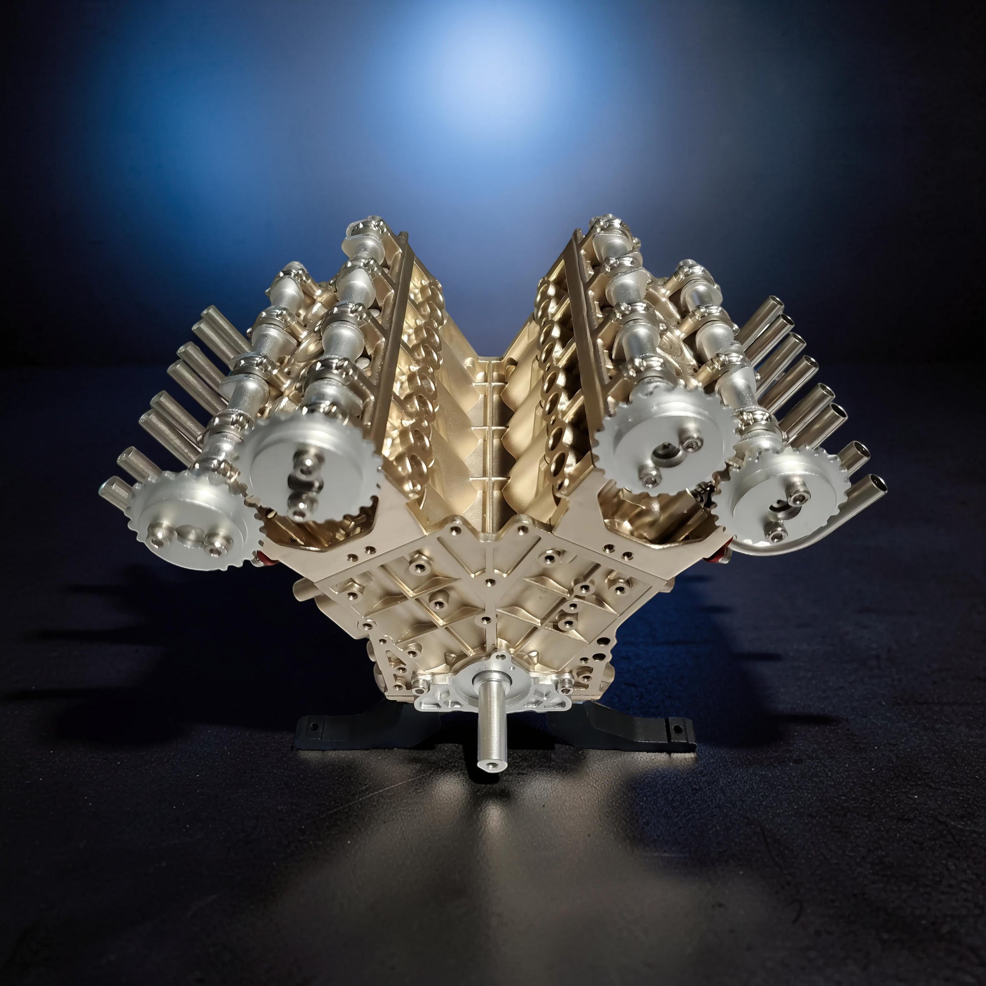 The Curious Mind V8 car engine DIY kit, a detailed metal mechanical model with gold and silver components, displayed on a stand.