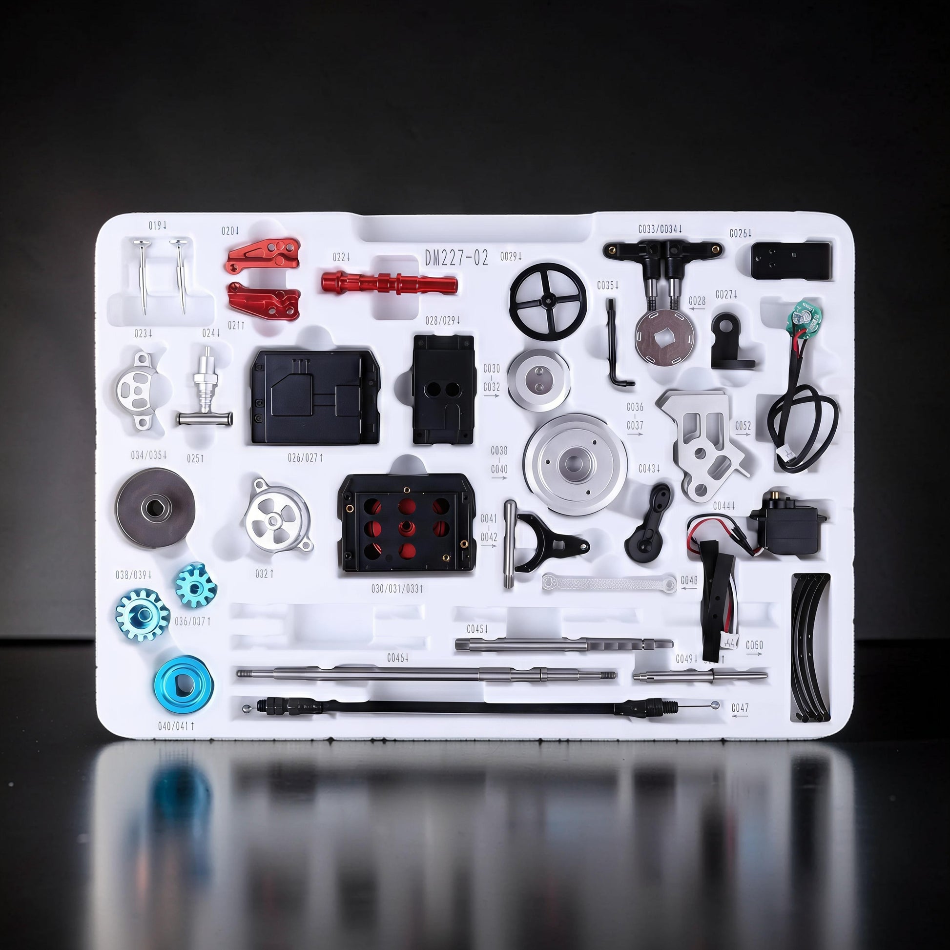 The Curious Mind Vintage Classic Car DIY Kit metal mechanical model parts laid out in a white tray. Includes gears, screws, and electronic components.
