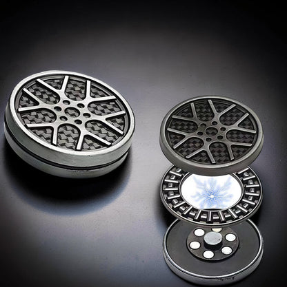 The Curious Mind Wheel Hub Coin Clicker fidget toy with a silver metal rim and carbon fiber pattern. Disassembled view shows internal components.