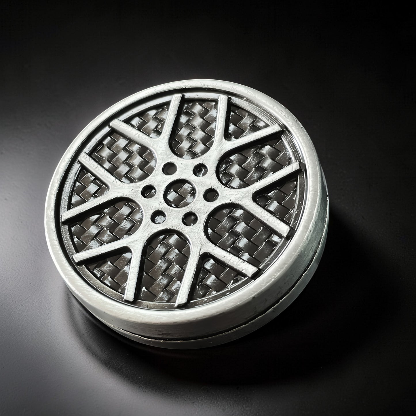 The Curious Mind Wheel Hub Coin Clicker fidget toy in silver metal with a carbon fiber pattern wheel design.