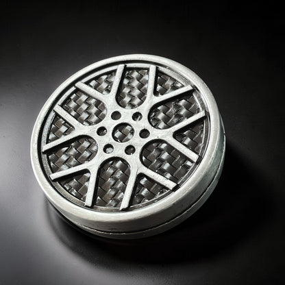 The Curious Mind Wheel Hub Coin Clicker fidget toy in silver metal with a carbon fiber pattern wheel design.