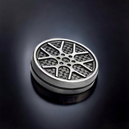 The Curious Mind Wheel Hub Coin Clicker fidget toy with a silver metal rim and a black carbon fiber pattern wheel design.