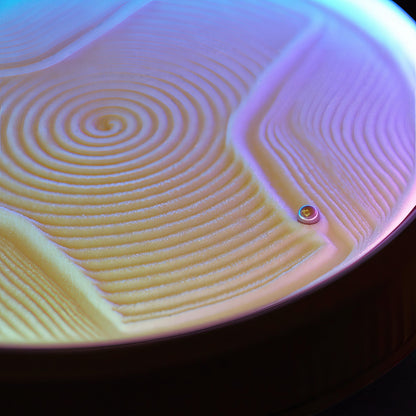 The Curious Mind Kinetic Sand Painting Machine with yellow sand creating swirling patterns under purple and blue light.