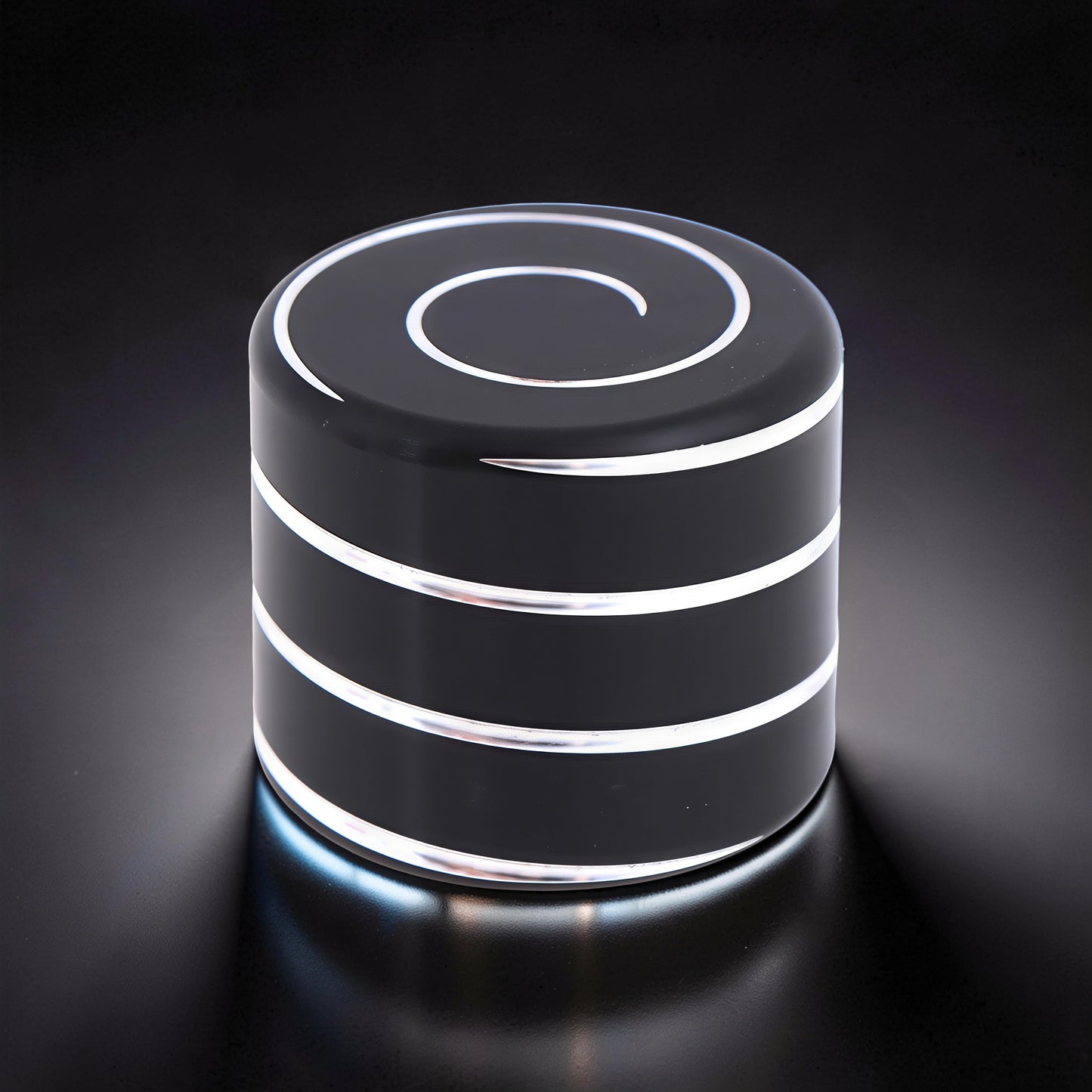 The Curious Mind Vortecon Kinetic Desk Spinner, a weighted black metal cylinder with silver spiral top and bands, for focus and stress relief.