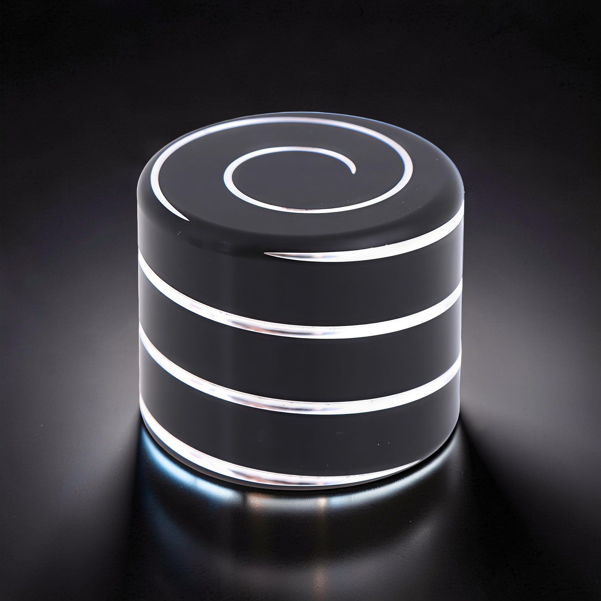 The Curious Mind Vortecon Kinetic Desk Spinner, a weighted black metal cylinder with silver spiral top and bands, for focus and stress relief.