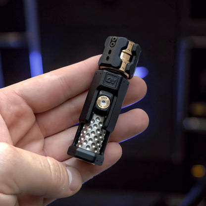 The Curious Mind Musketeers Snap Coin Clicker fidget toy in black metal with gold accents and a textured grip.