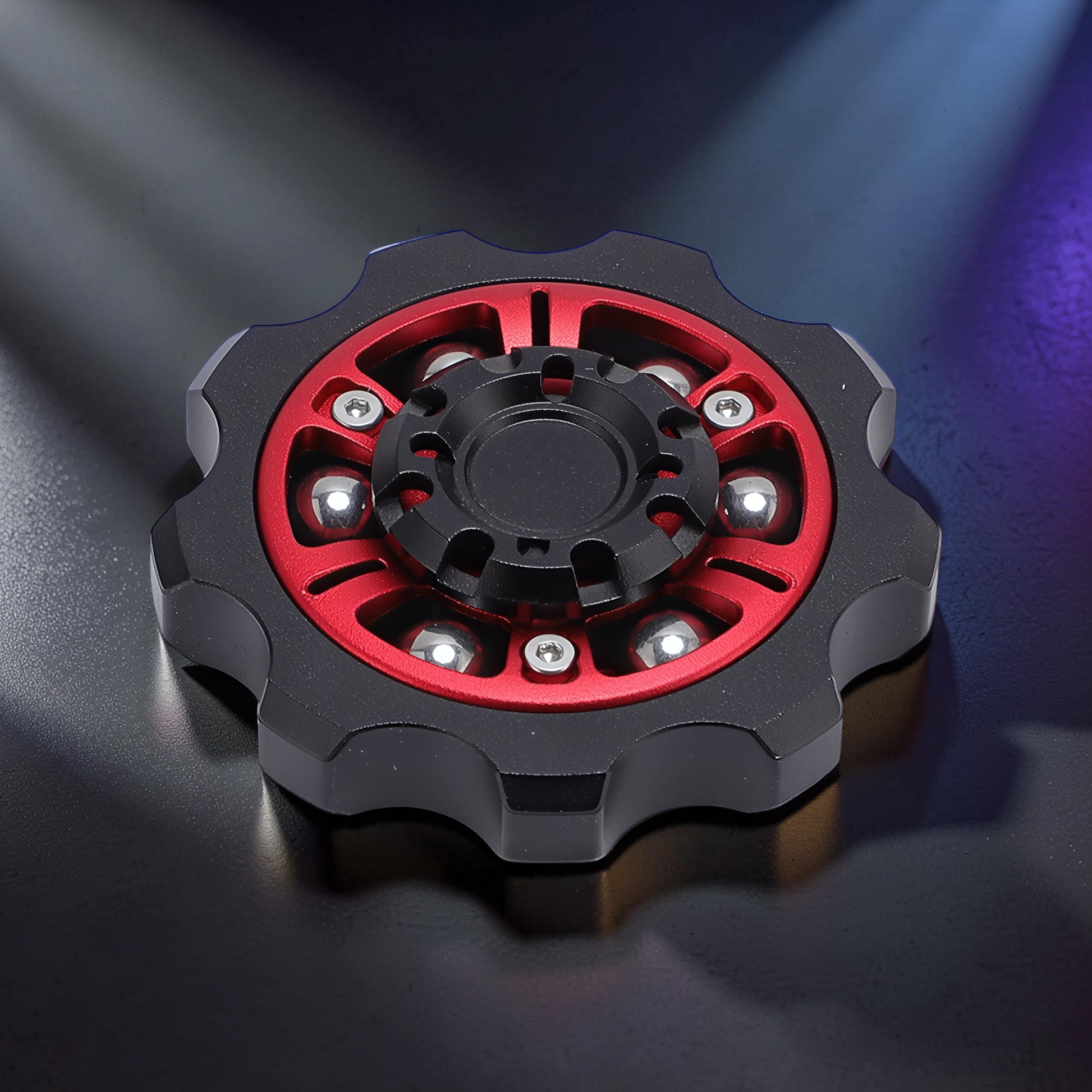 The Curious Mind Six-Bead Gear Spinner: black and red metal fidget spinner with six silver ball bearings, gear-like design.