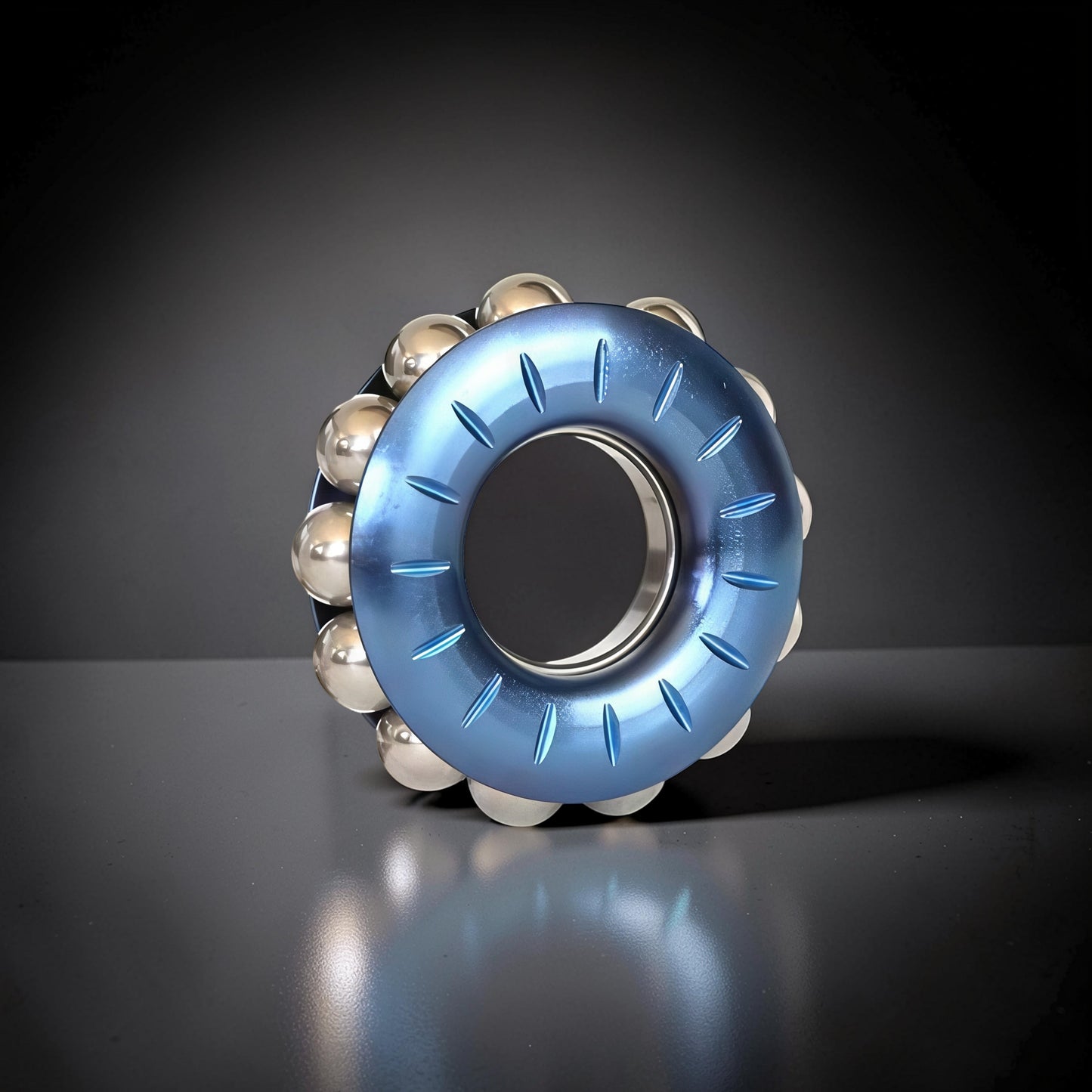 The Curious Mind blue metal bead wheel spinner with a textured rim and silver ball bearings. A premium fidget toy for focus and desk display.