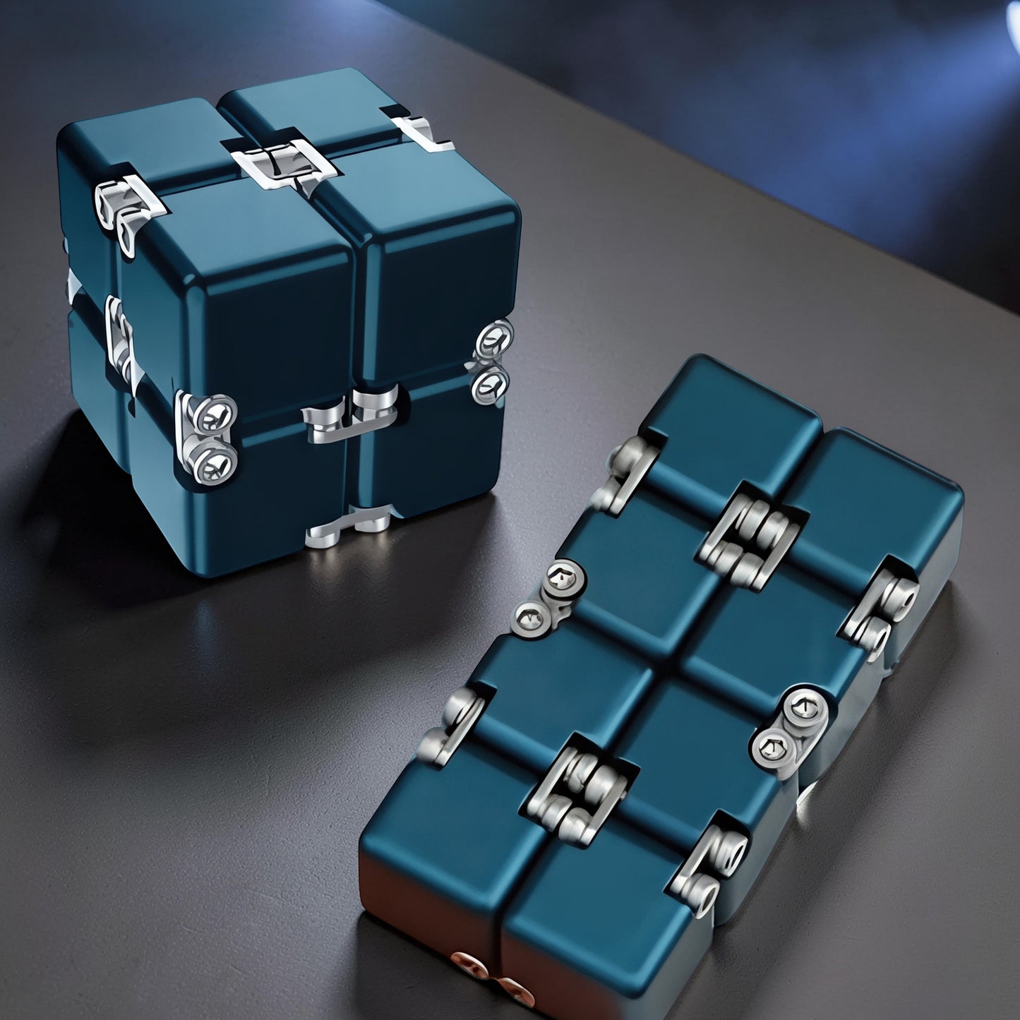 The Curious Mind Unlimited Magic Fidget Cube in dark blue metal, a compact desk toy that folds and unfolds.