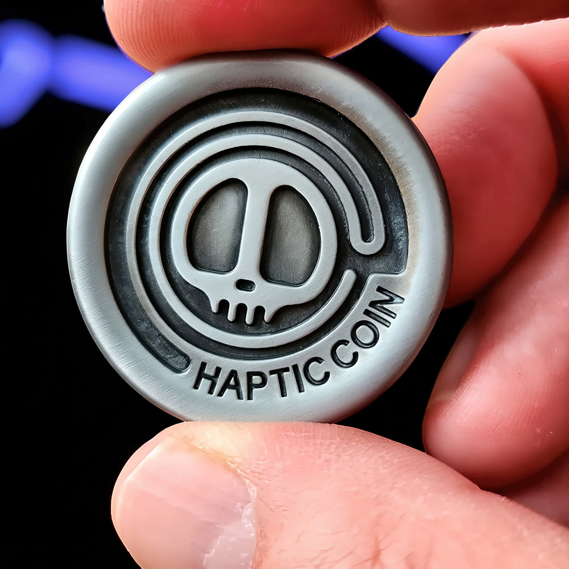 The Curious Mind Demon Coin Push Card Clicker, a silver metal fidget toy with a skull design and "HAPTIC COIN" text.