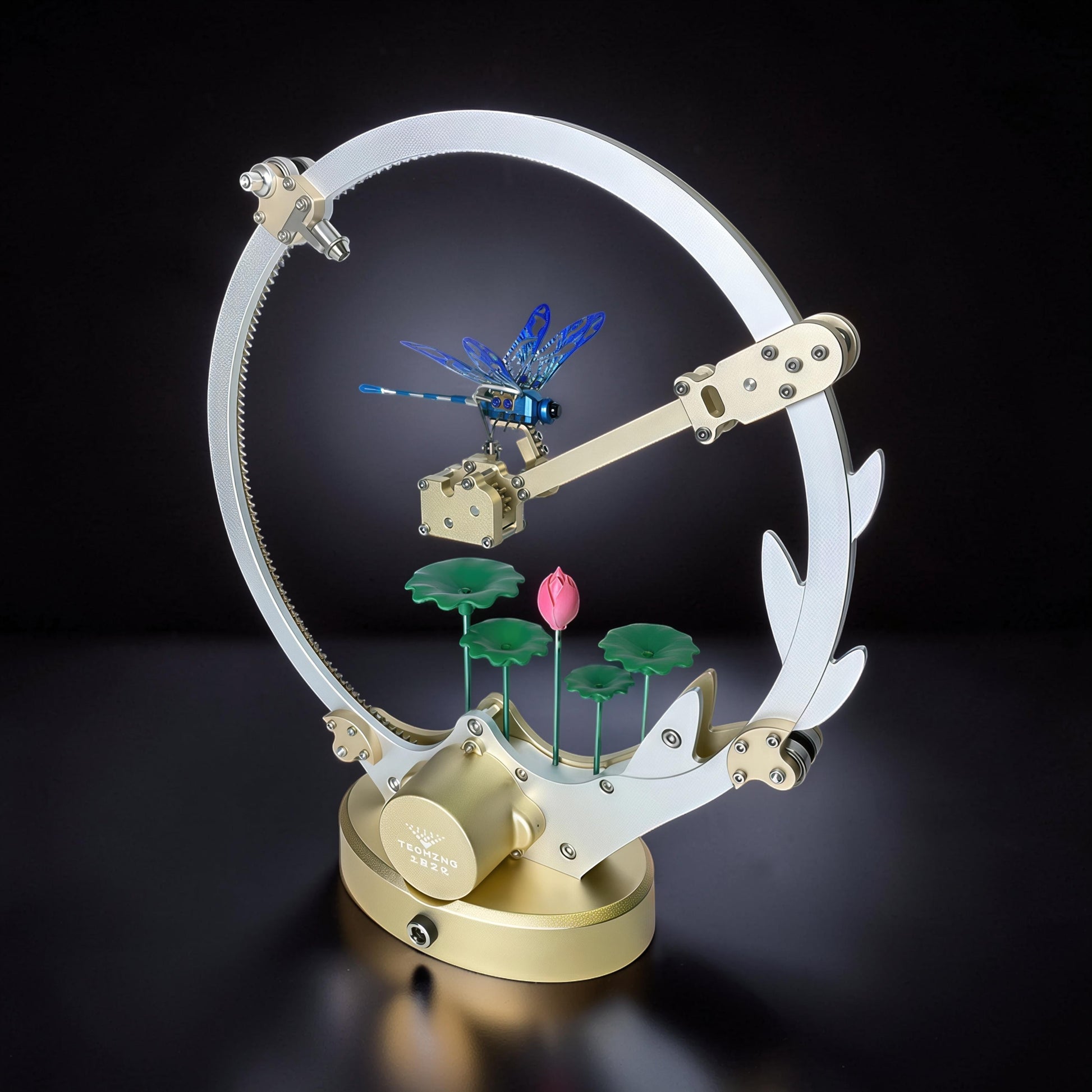The Curious Mind Flying Dragonfly Kinetic DIY Kit, a metal mechanical model with a blue dragonfly, lotus flowers, and a circular frame.