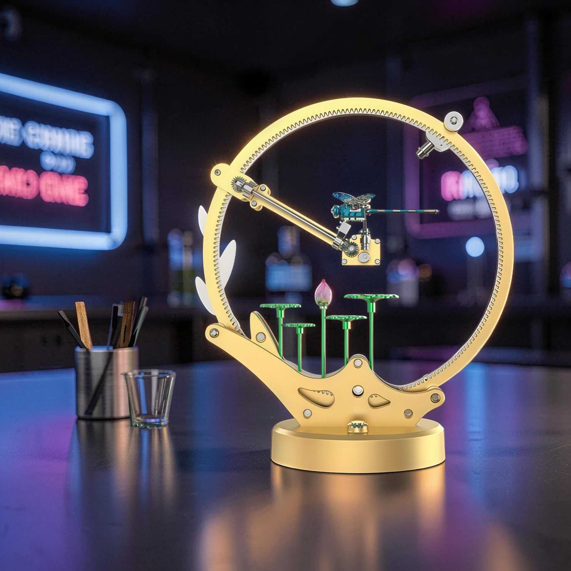 The Curious Mind Flying Dragonfly Kinetic DIY Kit, a mechanical metal model with a golden circular frame and a dragonfly in motion.
