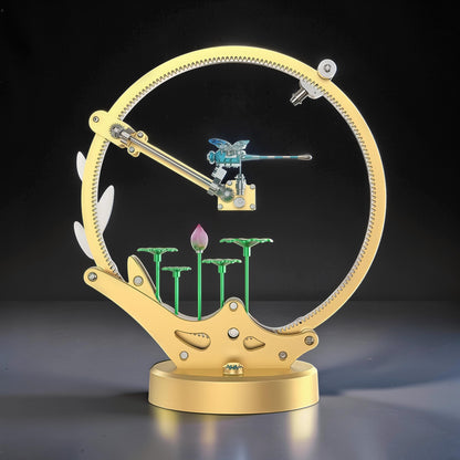 The Curious Mind Flying Dragonfly kinetic DIY kit, a mechanical metal model with a blue dragonfly, lotus flowers, and a large golden gear.