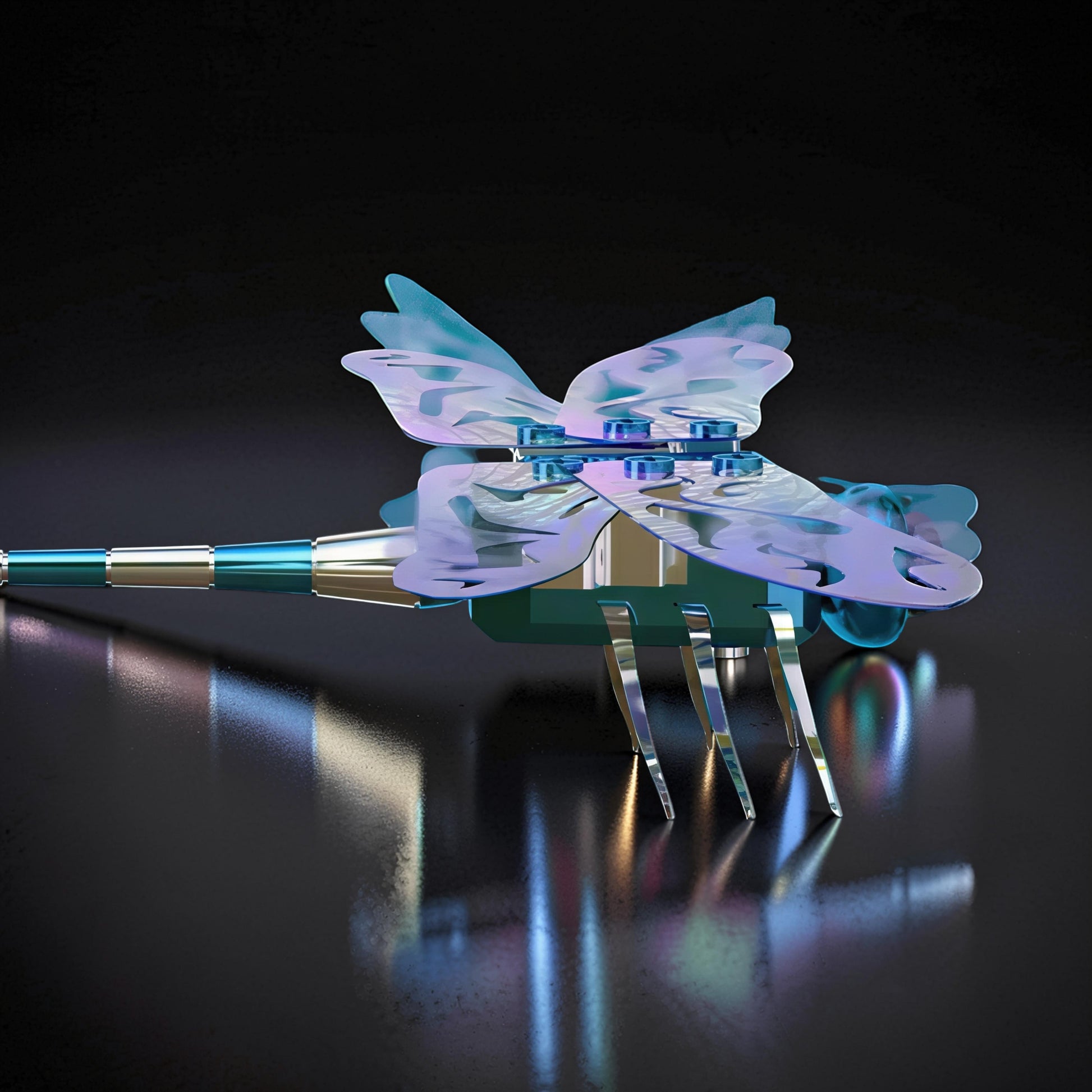 The Curious Mind Flying Dragonfly Kinetic DIY Kit, a metal mechanical model with iridescent wings and blue accents, displayed on a reflective surface.