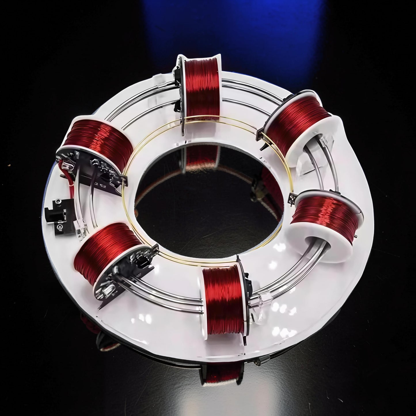 The Curious Mind High-Tech Electromagnetic Coil Accelerator Display, a circular metal and acrylic science toy with red coils.