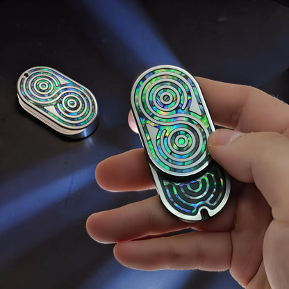 The Curious Mind Fritillary Push Slider fidget toy with iridescent abalone shell inlay and silver metal casing, held in hand.