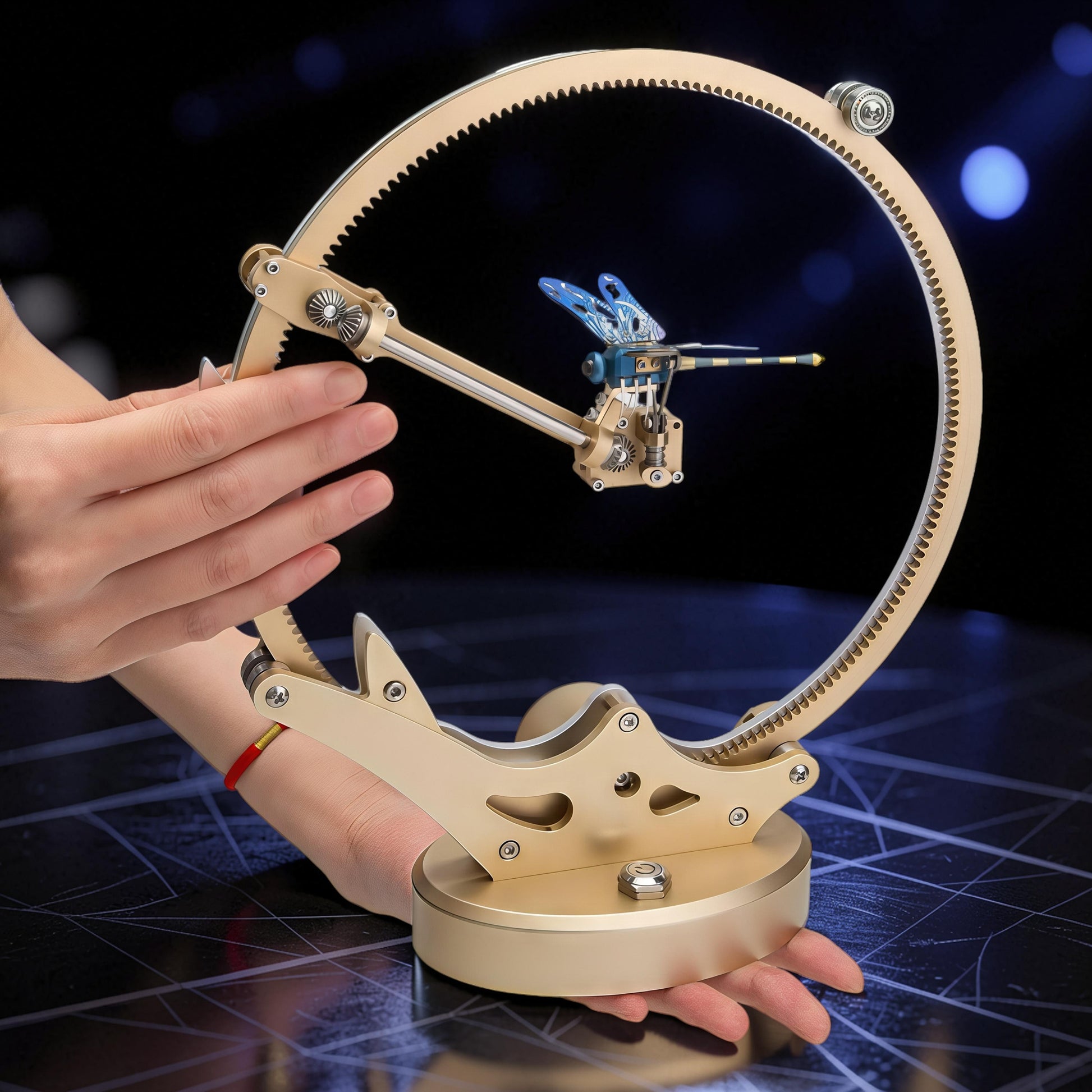 The Curious Mind Flying Dragonfly Kinetic DIY Kit, a metal mechanical model with blue wings and intricate gears, displayed on a circular track.