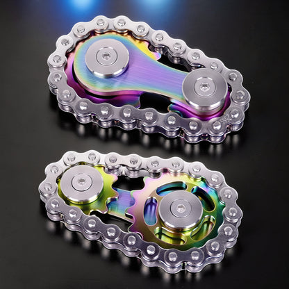The Curious Mind Gear Chain Sprocket Spinner, a metal fidget toy with a rainbow iridescent finish and silver chain links.