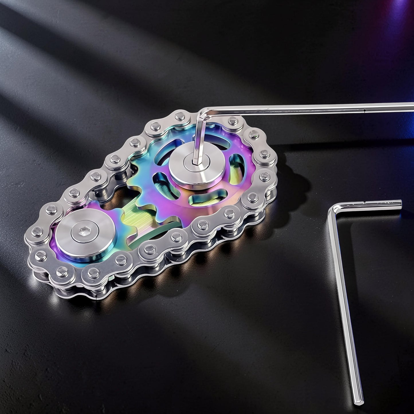 The Curious Mind Gear Chain Sprocket Spinner, a metal fidget toy with rainbow-colored gears and a silver chain.