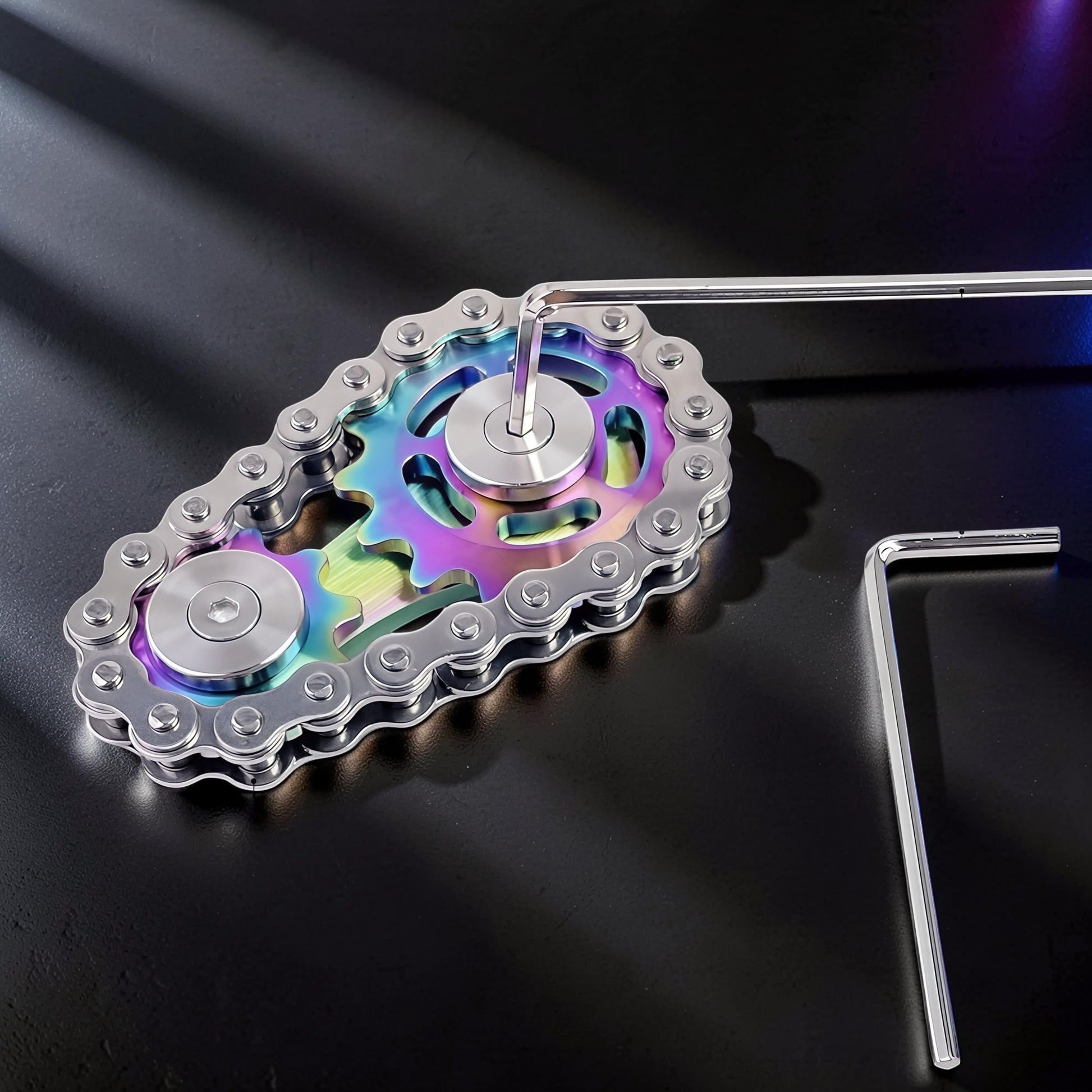 The Curious Mind Gear Chain Sprocket Spinner, a metal fidget toy with rainbow-colored gears and a silver chain.