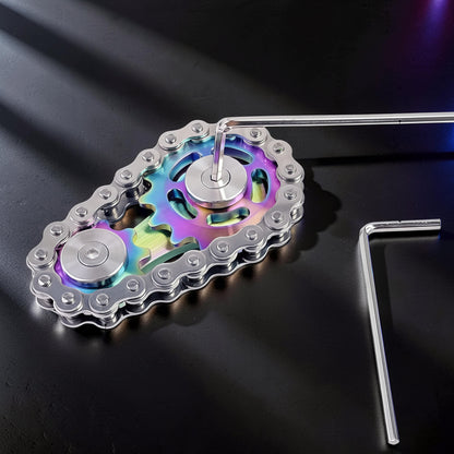 The Curious Mind Gear Chain Sprocket Spinner, a metal fidget toy with rainbow-colored gears and a silver chain.