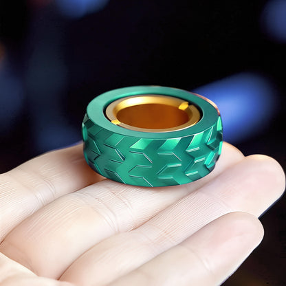 The Curious Mind green metal haptic ring with gold interior, tire tread design. Compact fidget toy for focus and stress relief.