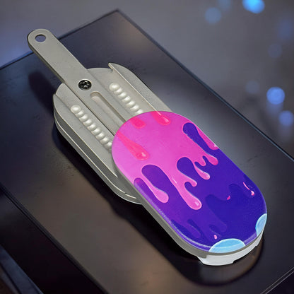 The Curious Mind Ice Cream Push Card Clicker fidget toy with pink and purple dripping design on a metal base.