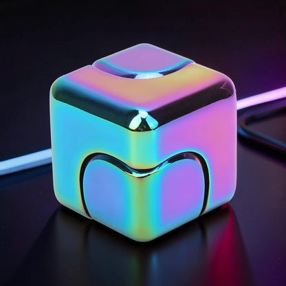 The Curious Mind iridescent metal spinner cube fidget toy with a compact, geometric design and a rainbow-like finish.